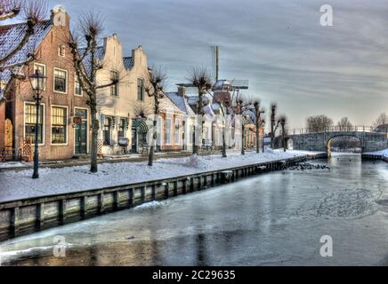 Vue d'hiver d'une rangée de maisons historiques avec un petit pont dans le village pittoresque de Sloten aux pays-Bas Banque D'Images