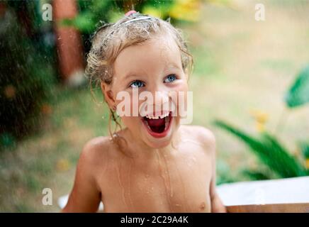 Gros plan portrait de la petite fille heureuse mignon profiter de la pluie d'été Banque D'Images