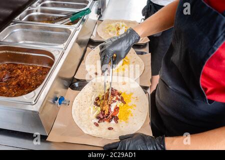 Femme préparant burrito dans un camion alimentaire Mettre les ingrédients dans le pain Tortilla Banque D'Images