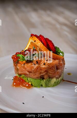 Délicieux tartre de saumon et d'avocat servi avec des fraises aux algues wakame et des œufs de poisson-lumière. Banque D'Images