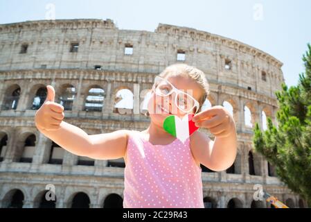 Drapeau Italien Girl Wearing Sunglasses, Holding Heart et Showing thumb up près de Colisée, Rome, Italie Banque D'Images