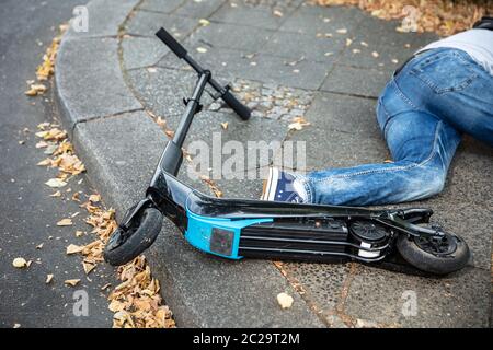 Homme inconscient allongé sur le béton rue après accident avec un Scooter électrique Banque D'Images