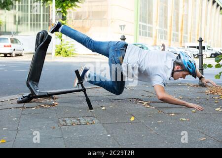 Homme qui tombe d'accident sur l'E-Scooter Street Banque D'Images