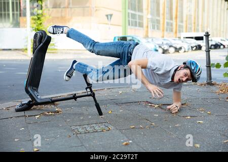 Homme qui tombe d'accident sur l'E-Scooter Street Banque D'Images