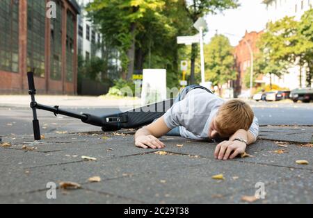 Homme inconscient allongé sur le béton rue après accident avec un Scooter électrique Banque D'Images