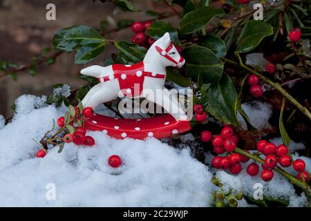 encore la vie avec peu de céramique cheval balançant ornement de noël, les baies rouges et un peu de neige Banque D'Images