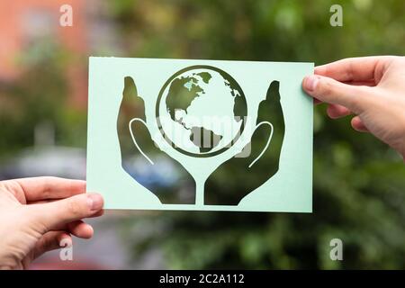 Mains tenant les mains avec du papier de protection à l'extérieur de la Terre Banque D'Images