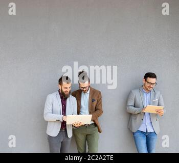 Des hommes d'affaires joyeux et joyeux utilisant un ordinateur portable à l'extérieur de la réunion Banque D'Images