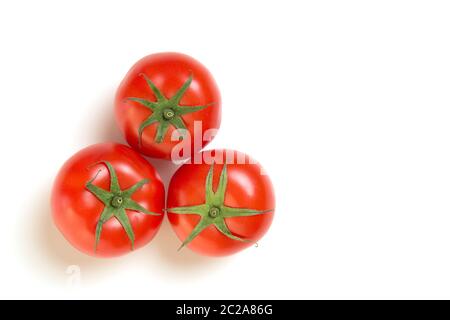 Trois vraies tomates dans un triangle vu d'un grand angle sur un fond blanc Banque D'Images