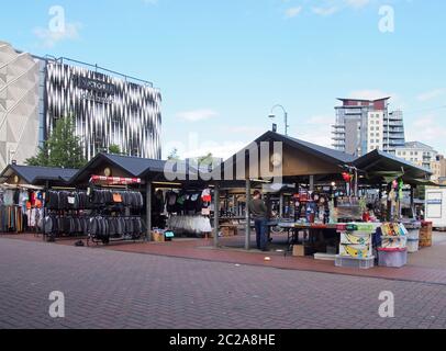 marché extérieur de leeds avec des gens qui font du shopping dans des stands traditionnels vendant des vêtements et de la nourriture en face de la moderne victoria quart Banque D'Images