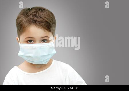 Peu Caucasian boy in medical masque sur fond isolé Banque D'Images