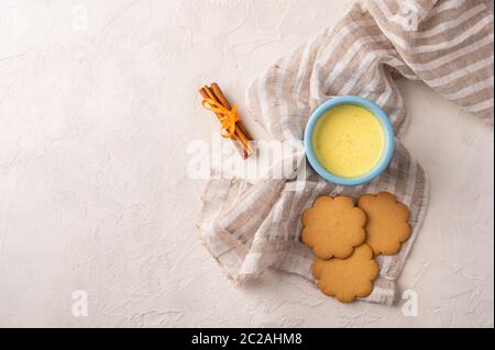 Deux tasses bleues avec thé traditionnel indien masala chai, bâtonnets de cannelle et biscuits sur une serviette en lin sur fond clair. Vue de dessus avec espace de copie Banque D'Images