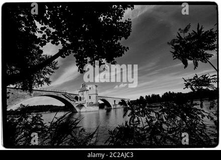 Pont d'Avignon. Le Pont Saint-Bénézet, Pont d'Avignon, 1988 Wikipeadia : le Pont Saint-Bénézet, également connu sous le nom de Pont d'Avignon, est un pont médiéval célèbre dans la ville d'Avignon, dans le sud de la France. Un pont en bois enjambant le Rhône entre Villeneuve-lès-Avignon et Avignon fut construit entre 1177 et 1185. Ce premier pont fut détruit quarante ans plus tard, en 1226, lors de la croisade albigésienne, lorsque Louis VIII de France assiéga Avignon. À partir de 1234, le pont a été reconstruit avec 22 arches en pierre. Le pont en pierre a une longueur d'environ 900 m (980 yd) et une largeur de seulement 4.9 m (16 ft) Banque D'Images