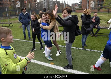 Les parents célèbrent avec les enfants après un match de football, à Milan. Banque D'Images