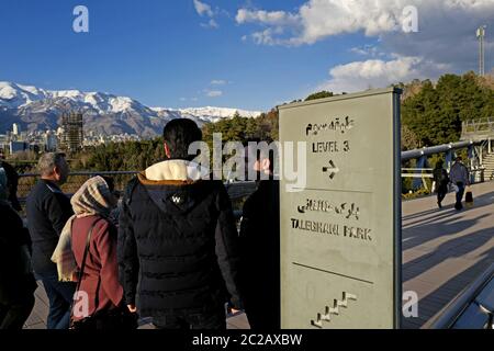 Le peuple iranien traverse le pont piétonnier moderne de Tabiat, jusqu'au parc Taleghani, avec les montagnes enneigées d'Alborz en arrière-plan, à Téhéran. Banque D'Images