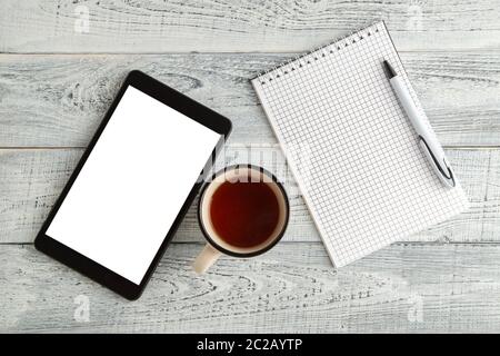 Tablette électronique noire, carnet en papier et une tasse de thé ou de café sur un fond en bois blanc vintage. Vue de la Banque D'Images