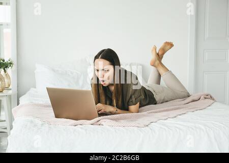 La fille utilise un ordinateur portable à la maison. Elle a vu des informations ou des nouvelles et a été agréablement surpris, en colère ou contrarié. Banque D'Images