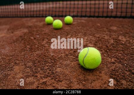 Vue rapprochée de balles de tennis près de la net, sur rouge artificiel de tennis. Banque D'Images