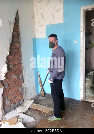 réparation à la maison. Un jeune homme frappe d'iro sur les anciennes plaques de plâtre de l'ère soviétique Banque D'Images