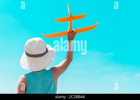 un enfant avec un avion contre le ciel bleu. vue arrière Banque D'Images