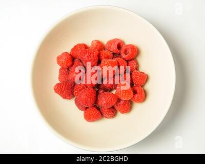 Un bol de framboises fraîches du dessus centré sur un fond blanc Banque D'Images