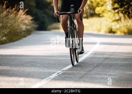 Gros plan d'un homme mature avec une forme de corps forte dans une tenue de cyclisme faisant de l'activité sportive sur vélo. Concept de mode de vie sain et de formation régulière. Banque D'Images