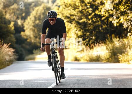 Portrait complet de l'homme actif en vêtements de sport et casque de protection en vélo avec fond flou de la nature estivale. Concept d'entraînement et r Banque D'Images