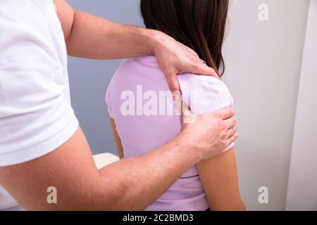 Professionnel Hommes Physiothérapeute massage des épaules blessé d'une femme lentement dans une clinique médicale Banque D'Images