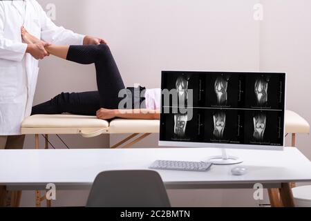 Bureau informatique en face de physiothérapeute en donnant à la thérapie du genou Woman Lying in Clinic Banque D'Images