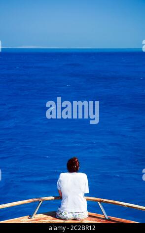 Femme de ses vingt ans regarde une étendue infinie de bleu calme océan Banque D'Images
