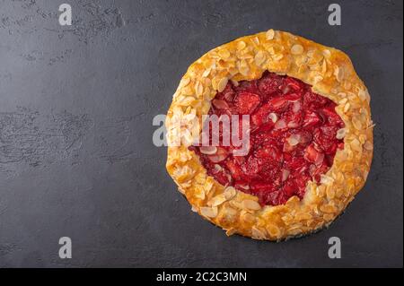 Tarte d'été maison aux fraises et aux pétales d'amande sur fond sombre. Vue de dessus avec espace de copie Banque D'Images