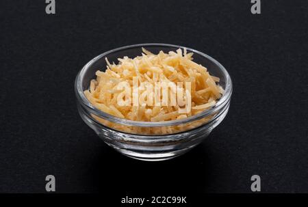 Fromage parmesan râpé dans un bol en verre, fond noir Banque D'Images