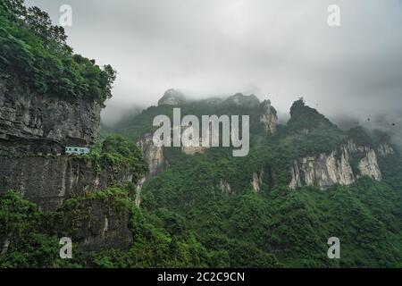 Bus avec les touristes de prendre la route jusqu'à la route sinueuse de 99 se tourne vers le haut de la montagne Tianmen, parc national de Zhangjiajie, Hunan, Chine Banque D'Images