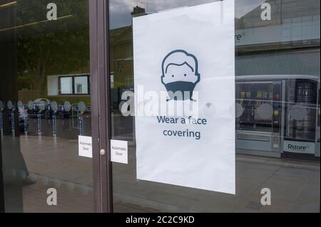 Affiche à l'entrée d'une gare ferroviaire demandant aux gens de porter un revêtement facial en raison de la pandémie du coronavirus en juin 2020, Angleterre, Royaume-Uni. Banque D'Images