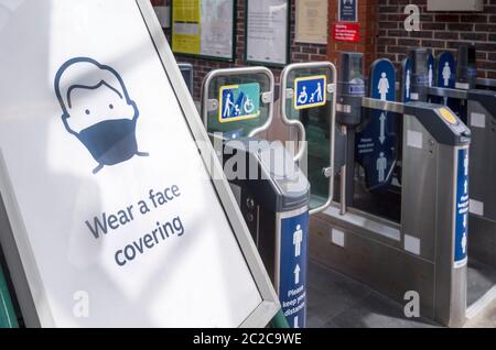 Affiche à l'entrée d'une gare ferroviaire demandant aux gens de porter un revêtement facial en raison de la pandémie du coronavirus en juin 2020, Angleterre, Royaume-Uni. Banque D'Images