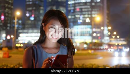 Femme l'utilisation de téléphone mobile en ville la nuit Banque D'Images
