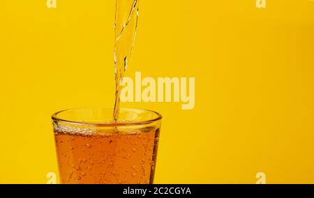 Le jus de pomme et verser dans le verre, isolé sur fond jaune Banque D'Images