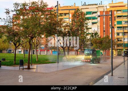 Arrosage machine de nettoyage rue par th.C. petit parc dans un quartier résidentiel avec des blocs d'appartements d'architecture moderne, Barcelone, Espagne Banque D'Images