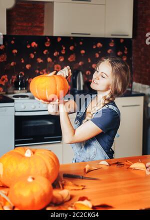 une belle femme blonde peint des citrouilles pour halloween à la maison sur la cuisine Banque D'Images