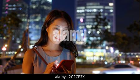 Femme l'utilisation de smart phone in city at night Banque D'Images
