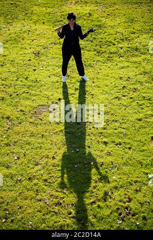 Vue aérienne d'un golfeur tenant un club de golf et un ballon et debout sur le Fairway avec ombre. Banque D'Images