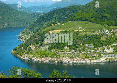 Vue aérienne sur Morcote avec le lac alpin de Lugano et la montagne en une journée ensoleillée au Tessin, Suisse. Banque D'Images