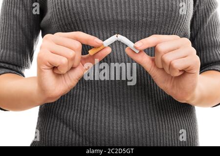 Pause/arrêter cette mauvaise habitude. Jeune femme briser une cigarette, isolé sur un fond blanc. Banque D'Images