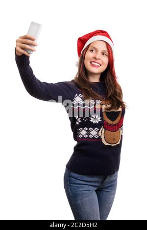 Jeune fille belle portant un chapeau de noël prenant un selfie, isolé sur fond blanc. Banque D'Images