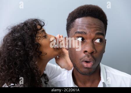 Businessman chuchotant à l'oreille des collègues In Office Banque D'Images