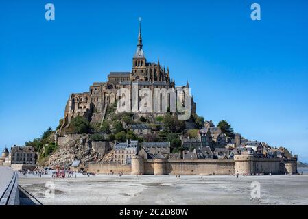 Abbaye du Mont Saint Michel à marée basse et touristes se rendant sur elle. Banque D'Images