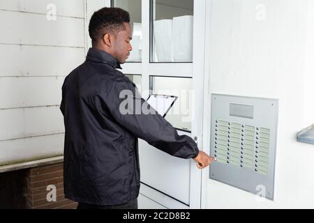 Homme debout en face de la maison cogne la porte Banque D'Images