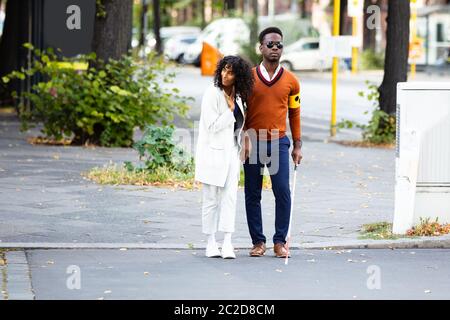 Jeune femme aider aveugle sur Street Banque D'Images