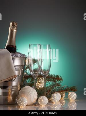 Encore plus de vie avec une bouteille de champagne dans un seau avec glace, deux flûtes à champagne vides, guirlande lumineuse LED et décorations de Noël. Noël et Banque D'Images