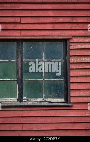 Détail de vieilles fenêtres rustiques et sales dans un ancien bâtiment en bois peint en rouge. Gros plan de l'extérieur. Banque D'Images